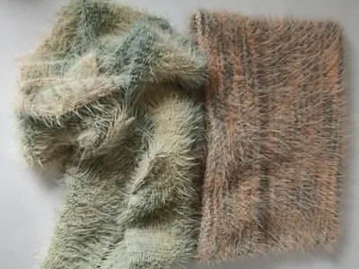 Zwei Eyelash-Garn-Strickproben in Salbeigrün und Altrosa auf weißem Untergrund
