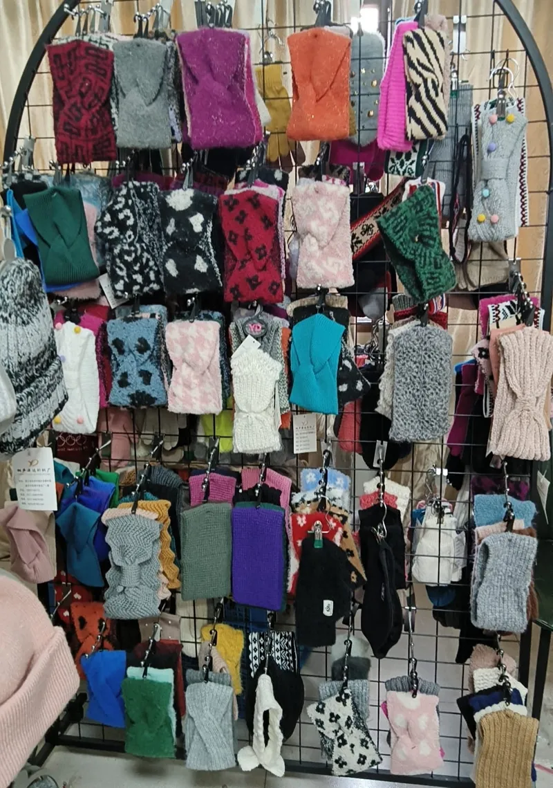 Großes Einzelhandelsregal mit zahlreichen gestrickten Fingerhandschuhen und Fäustlingen in verschiedenen Farben, Mustern und Texturen