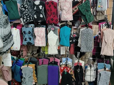 Großes Einzelhandelsregal mit zahlreichen gestrickten Fingerhandschuhen und Fäustlingen in verschiedenen Farben, Mustern und Texturen