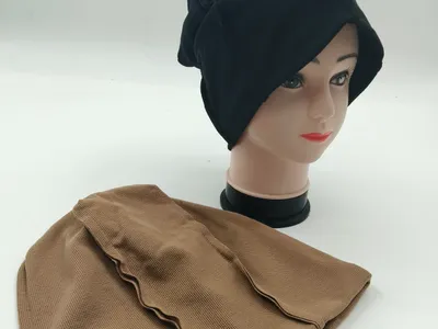 Lockere schwarze Strickmütze als Hijab-Unterziehmütze auf Modellkopf, daneben eine beigefarbene strukturierte Innenkappe auf weißem Untergrund