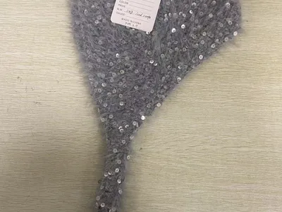 Schwarze Ohrenwärmer mit flauschigen Ohrmuscheln und gestricktem Bügel mit weißer Aufschrift und rotem Streifenmuster, weißer Hintergrund