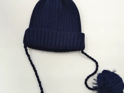 Marineblaue Winterstrickmütze mit Bommeln auf der Spitze und zwei langen geflochtenen Zopfbändern mit großen Endpompons