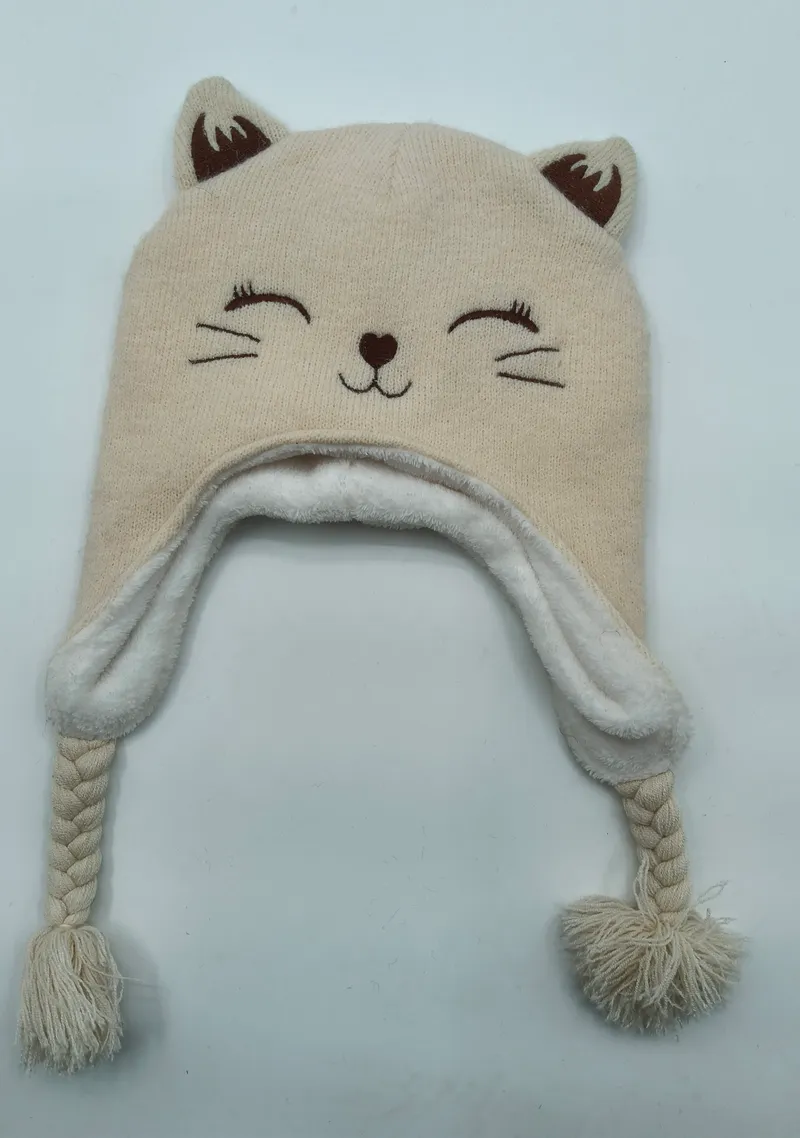 Cremefarbene gestrickte Wintermütze in Katzendesign mit Ohrklappen, geflochtenen Bindeschnüren, Pompons, weichem Fleecefutter und bestickten Katzengesichtsdetails