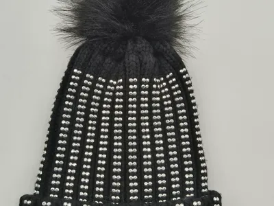 Schwarze Rippenstrickmütze dicht besetzt mit silbernen Kristallnieten und großem schwarzem Kunstfell-Bommel auf der Spitze
