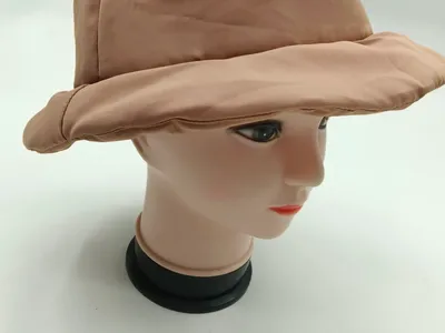 Beigefarbene wattierte Nylon-Bucket-Hat auf Hutständer, mit breiter Krempe und charakteristischer Steppnähten an der Außenseite
