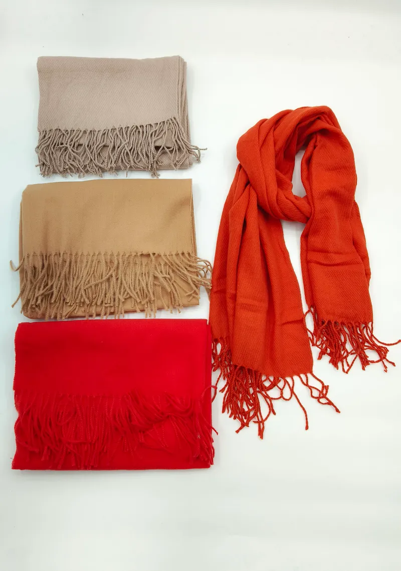 Vier unifarbene Schals im Pashmina-Stil mit weichen Fransenkanten in Beige, Kamelbraun, Rot und Terrakotta – einer ausgelegt, drei gefaltet auf weißem Hintergrund