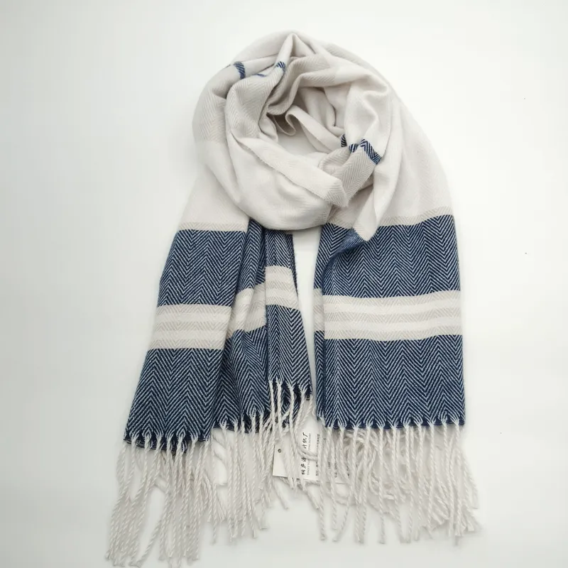 Gewebter Schal in Marineblau und Creme mit markantem Fischgrat-Muster, breiten Streifen und Quasten-Fransen, aufgerollt auf weißem Hintergrund