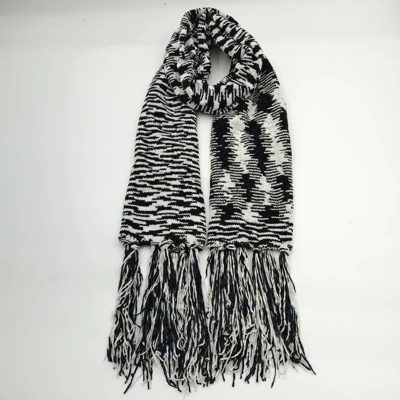 Schwarz-weißer Grobstrickschal mit grafischem Zebra-Streifenmuster und langen dekorativen Fransenenden, flach auf hellem Untergrund ausgelegt