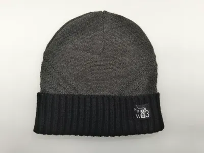 Grau gestrickte Beanie mit kontrastreichem schwarzem Rippenumschlagbund und eingenähtem Schriftzug-Label auf weißem Hintergrund