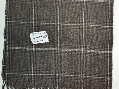 Draufsicht auf einen braun-weißen Webschal im Glen-Karo-Muster mit gedrehtem Fransensaum aus Polyester-Viskose-Gewebe