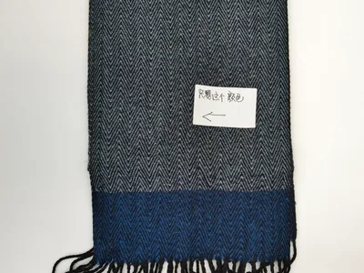 Grau-blauer Webschal mit Fischgrätmuster und zweifarbigem Farbblock-Design sowie schwarzem Fransensaum, flach auf weißem Untergrund fotografiert
