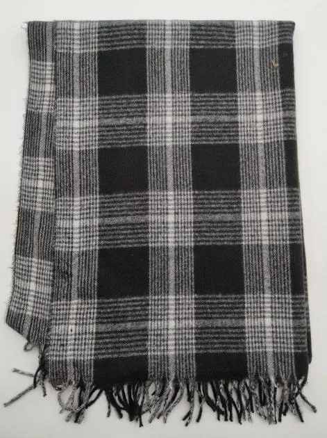 Zusammengelegte schwarz-weiße Tartan-Karierwolldecke aus gewebtem Stoff mit geknoteten Fransenenden auf weißem Hintergrund