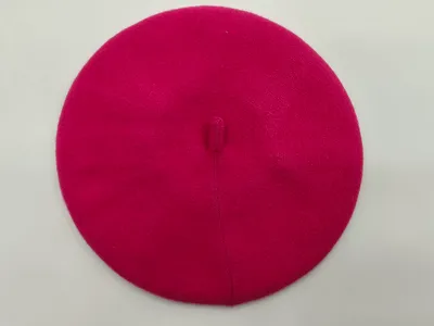 Pinkfarbenes Damenbarett aus feiner Strickwolle mit Knopf an der Spitze, Draufsicht auf weißem Hintergrund
