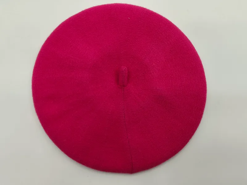 Pinkfarbenes Damenbarett aus feiner Strickwolle mit Knopf an der Spitze, Draufsicht auf weißem Hintergrund