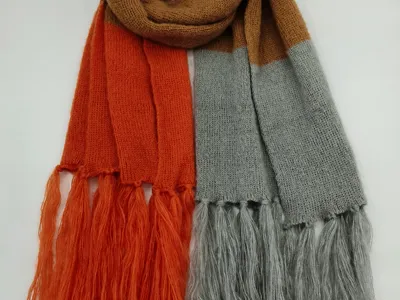 Gestrickter Colorblock-Schal in Rostrot, Grau und Kamelbraun mit langen Fransen an den Enden, flach fotografiert