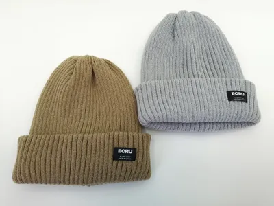 Zwei gerippte Umschlag-Beanies in Khaki und Hellgrau nebeneinander, mit schwarzem Webklabel am Umschlag