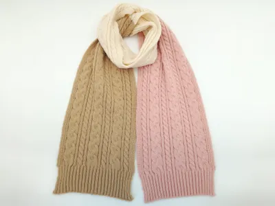 Zopfstrick-Schal mit beigen und rosa Enden, zu einer cremefarbenen Mittelschlaufe gedreht, flach auf weißem Hintergrund