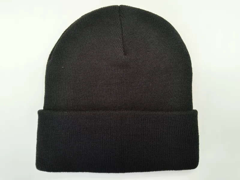 Schlichte schwarze Rippenstrick-Mütze mit gefaltetem Umschlag, flach auf weißem Hintergrund, unisex