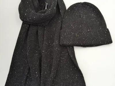 Dunkelgrauer Strickschal mit weißem Fleckenmuster und dazu passende Strickmütze aus strukturiertem Rippgarn