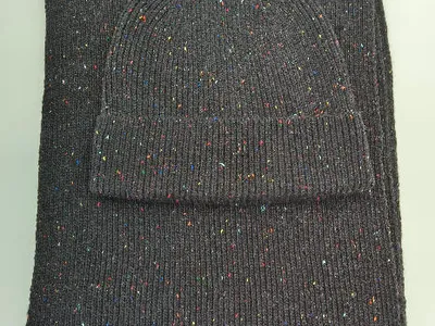 Dunkelgraue Strickmütze und passender Schal mit buntem Konfetti-Fleckenmuster auf weißem Hintergrund