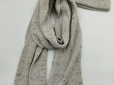 Hellgrauer Rippstrickschal und passende Beanie-Mütze mit dunklem Fleckenmuster vor weißem Hintergrund