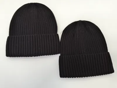 Zwei schwarze Rippstrick-Beanies mit Umschlagrand in verschiedenen Größen auf weißem Untergrund