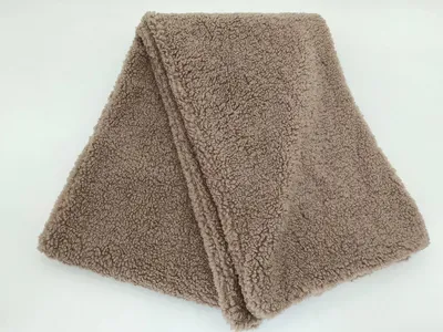 Gefaltete Taupe-Sherpa-Fleece-Kuscheldecke mit lockig-strukturierter Plüschoberfläche und sauberem Abschlussrand auf weißem Hintergrund