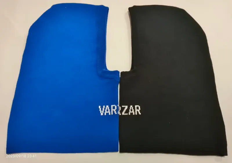 Blau-schwarze zweifarbige gestrickte Sturmhaube flach liegend mit Gesichtsausschnitt und Logoprint auf der schwarzen Seite