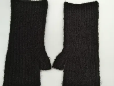Paar schwarze Rippstrick-Armstulpen mit flauschig-weichem Mohair-Anteil und Daumenöffnung, Flachaufnahme auf weißem Hintergrund