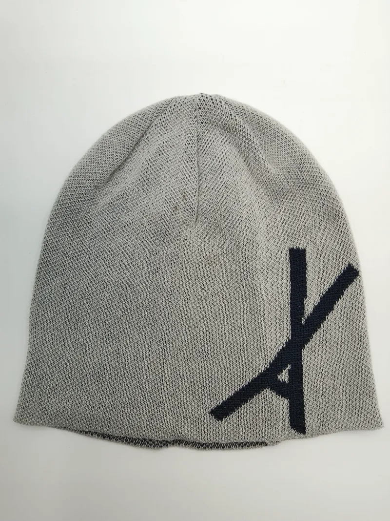 Hellgraue Feinstrick-Slouch-Beanie mit großem navyblauen Schriftzug auf der Vorderseite, Draufsicht auf weißem Untergrund