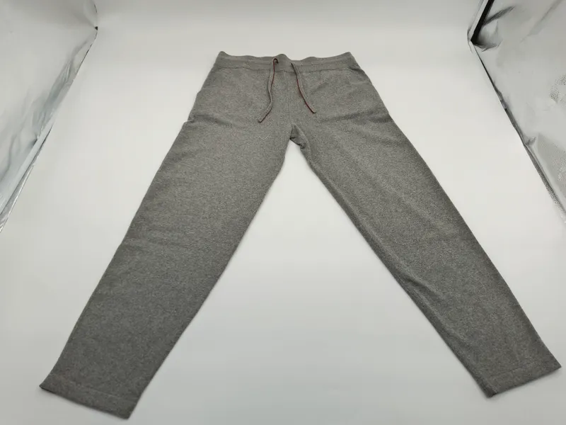Aufgefaltete graue Melange-Jogginghose mit schmalem Schnitt, braunem Kordelzug am Bund und Seitentaschen in Produktfotografie