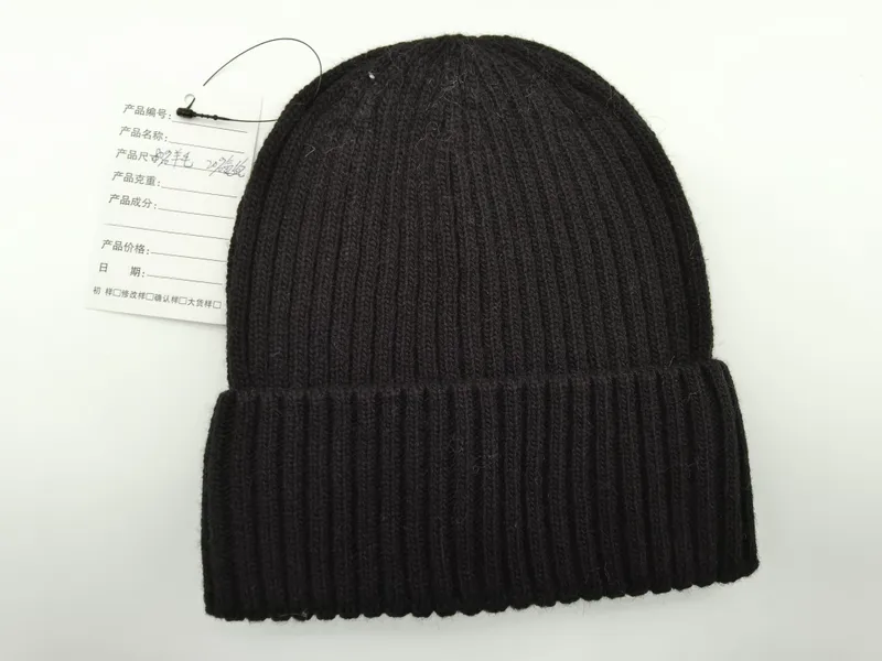 Schwarze Grobstrick-Beanie mit gefaltetem Krempenrand und angehängtem Produktetikett, Flatlay-Aufnahme auf weißem Hintergrund