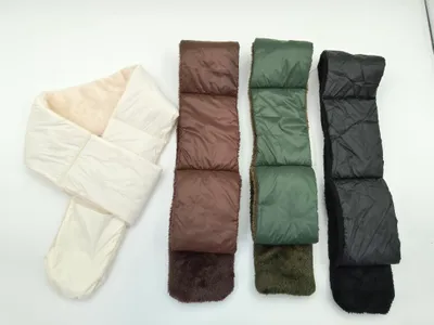 Vier gesteppte Puffer-Schals mit Kunstfell-Innenfutter nebeneinander in Creme, Braun, Olivgrün und Schwarz auf hellem Hintergrund