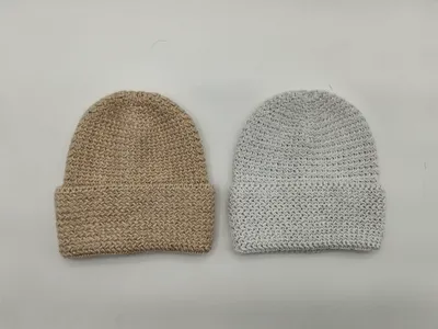 Zwei Grobstrick-Beanies mit gefaltetem Rand in Beige und Hellgrau nebeneinander, mit strukturiertem Flechtmuster in Draufsicht