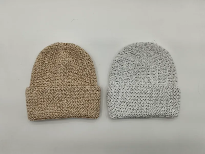 Zwei Grobstrick-Beanies mit gefaltetem Rand in Beige und Hellgrau nebeneinander, mit strukturiertem Flechtmuster in Draufsicht