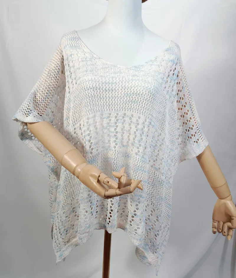 Weiß-blaues Multicolor-Häkel-Poncho-Top mit Kurzarm auf einer Schneiderpuppe, halbtransparentes Spitzenmuster in der Gesamtansicht