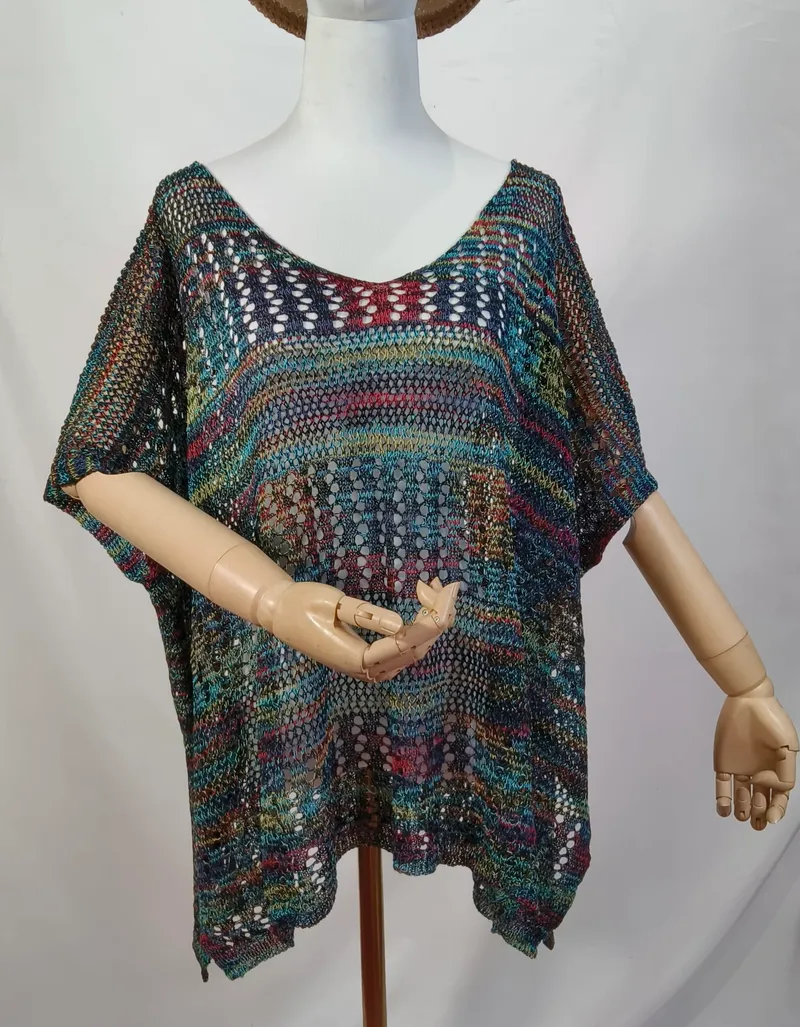 Buntes Boho-Häkelponcho mit Kurzarm auf einer Schneiderpuppe, mit Farbakzenten in Petrol, Rot und Gold
