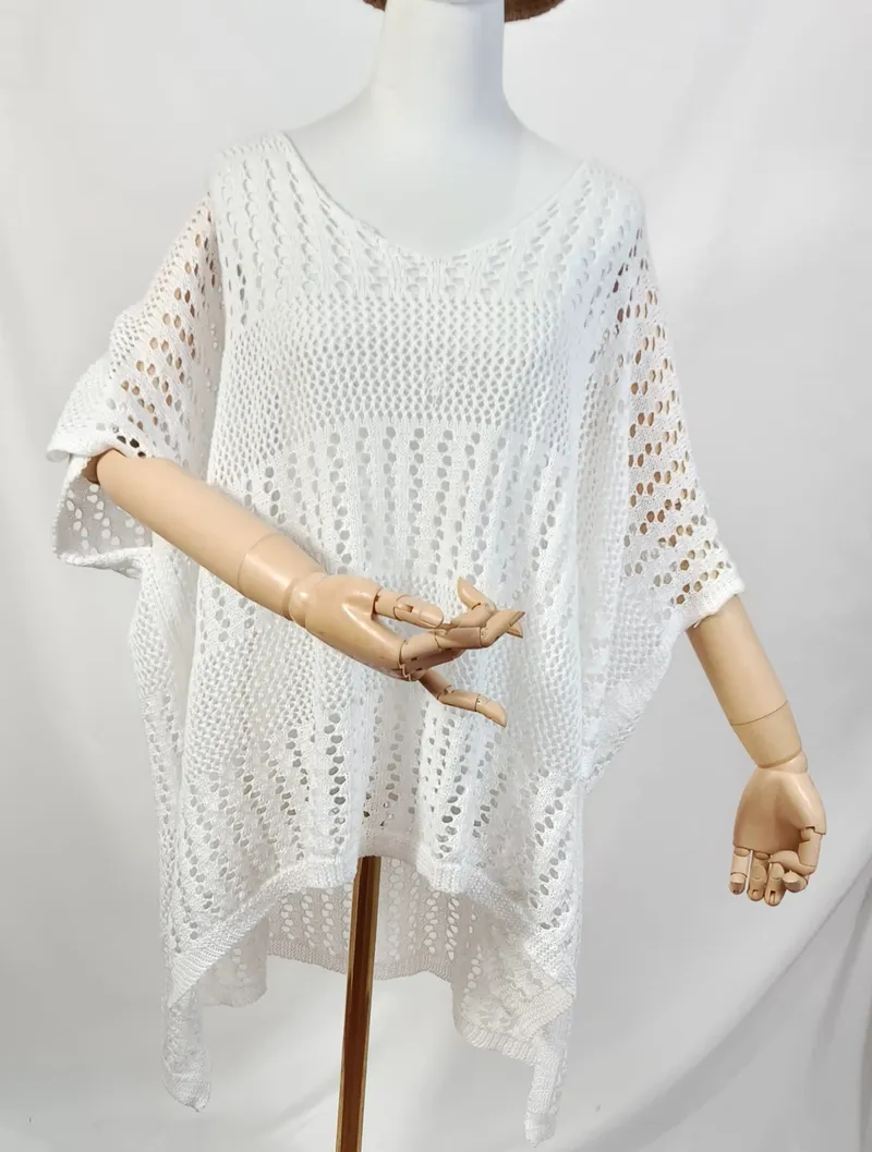 Weißes Oversized-Häkelponcho mit V-Ausschnitt und Kurzarm auf einer Schneiderpuppe mit Holzhänden in Gesamtansicht