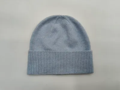 Weiche hellblaue Strickmütze mit breitem umgeklapptem Rippbund, flach auf weißem Hintergrund liegend, nahtloser Mützenabschluss