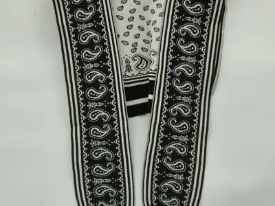 Ärmellose Strickjacke mit Paisley-Jacquardmuster in Schwarz und Weiß, gestreifter Abschluss, offen auf Kleiderbügel präsentiert