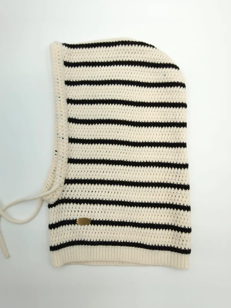 Creme-schwarz gestreifte Häkel-Balaclava flach liegend mit Ripprand, Schnürverschluss und kleinem goldenem Markenlabel