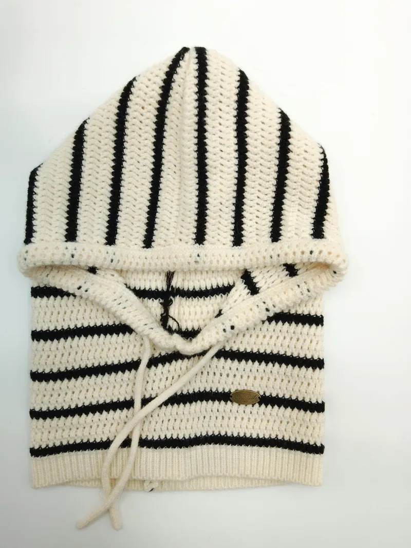 Gefalteter creme-schwarz gestreifter Häkel-Hoodie-Pullover mit Kordelzug-Kapuze und Rippbund, flach auf weißem Hintergrund