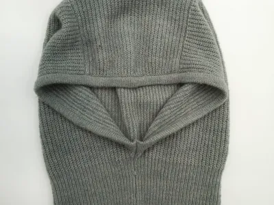 Graue Strick-Balaclava mit Rippenmuster als Gesichtsschutz, offene Gesichtsöffnung, Draufsicht auf weißem Untergrund