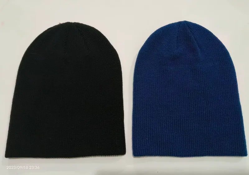 Zwei schlichte Slouchy-Beanies nebeneinander in Schwarz und Royalblau, gerippte Struktur ohne Bund, Studioaufnahme