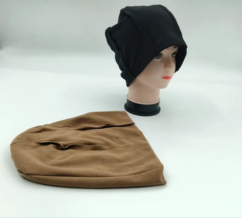Schwarze Waffelstrick-Slouchy-Beanie auf Mannequin-Kopf neben flach liegender brauner Beanie auf weißem Hintergrund