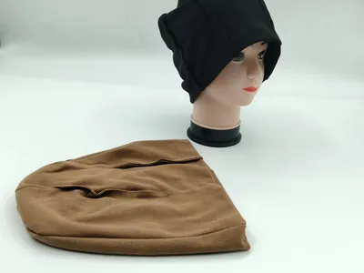 Schwarze Waffelstrick-Slouchy-Beanie auf Mannequin-Kopf neben flach liegender brauner Beanie auf weißem Hintergrund