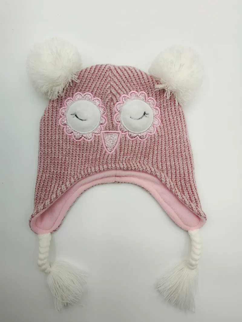 Rosa grob gestrickte Kinderwintermütze mit aufgesticktem Eulengesicht, weißen Bommeln, Ohrklappen und geflochtenen Quasten