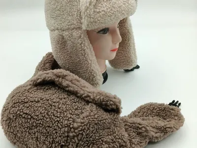 Zweifarbige Sherpa-Mütze in Creme und Beige mit weichem Fleece-Material und herunterklappbaren Ohrenschützern auf Hutständer