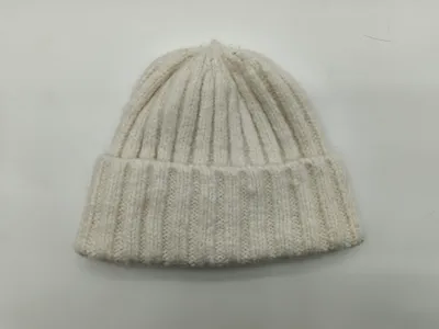 Cremefarbene Wintermütze mit grober Rippenstruktur und umgeschlagenem Bündchen, flach auf hellem Untergrund fotografiert