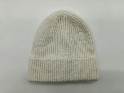 Hellbeige Rippenstrick-Wintermütze mit breitem Umschlagbund, flach auf grauem Hintergrund drapiert